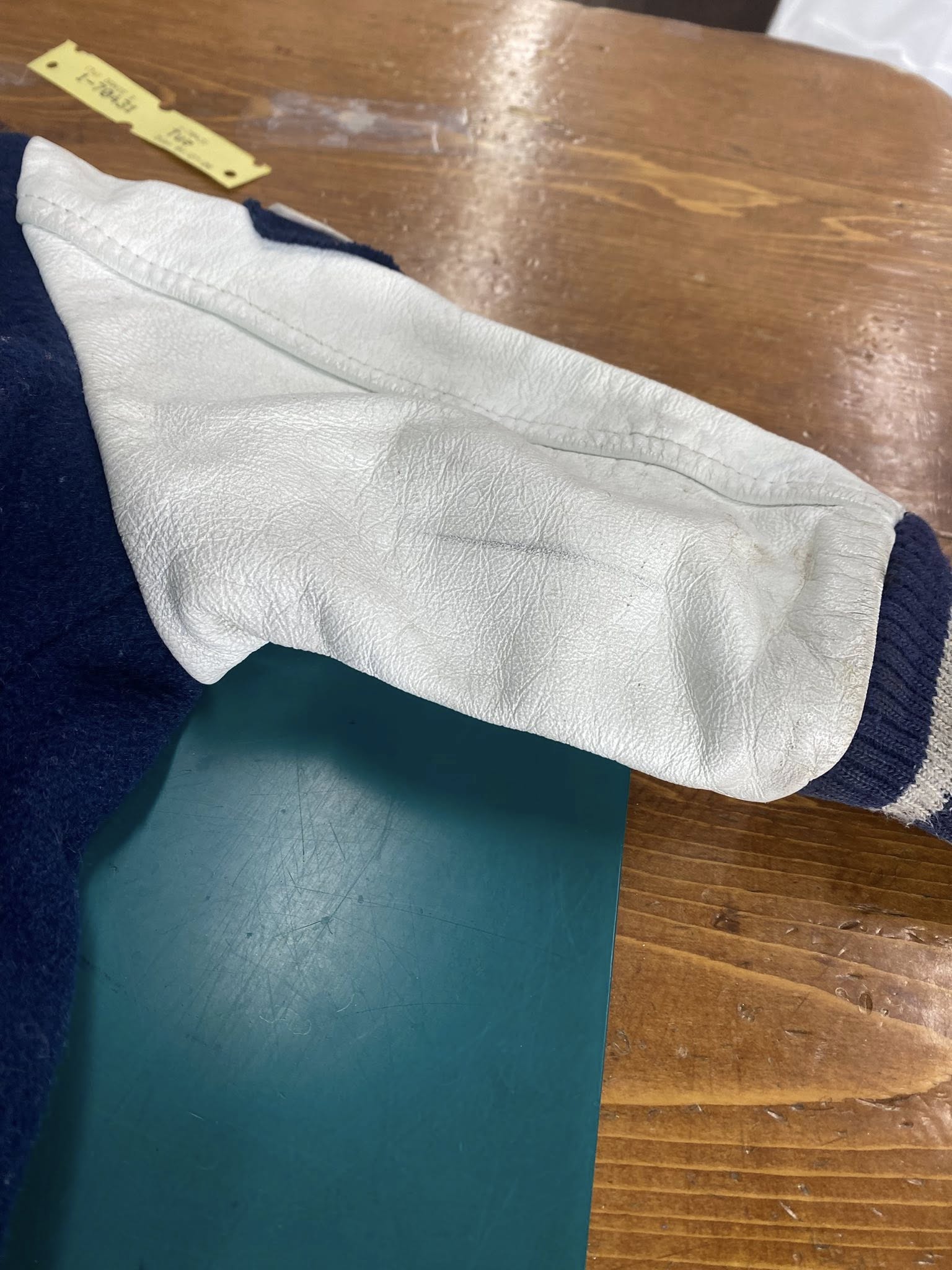 Varsity jacket leather sleeve restoration on the workbench at Pure Cleaners